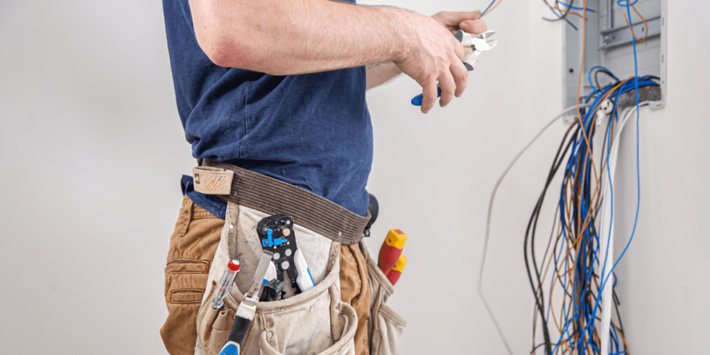 Electrician builder at work, examines the cable connection.
